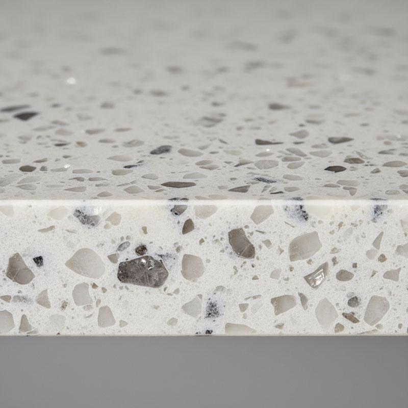 Cross-section macro photograph of engineered quartz stone showing natural quartz aggregate crystals bound by polymer resin matrix with visible pigment particles